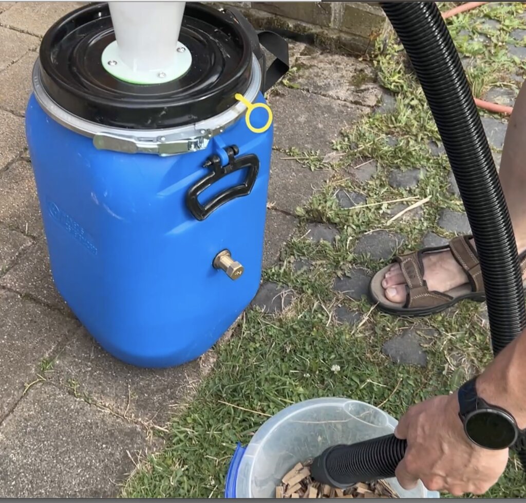 Das Bild zeigt die blaue Auffangtonne mit dem weißen Zyklonabscheider und den Eimer mit den Pappschnipseln